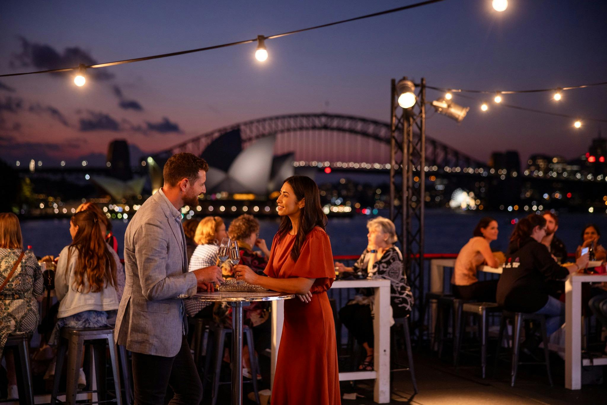 Guests share a drink in the Northern Terrace with spectacular Sydney Harbour views in the background