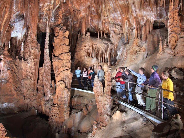 tour group inside a large cave standing on a walkway looking up at cave roof