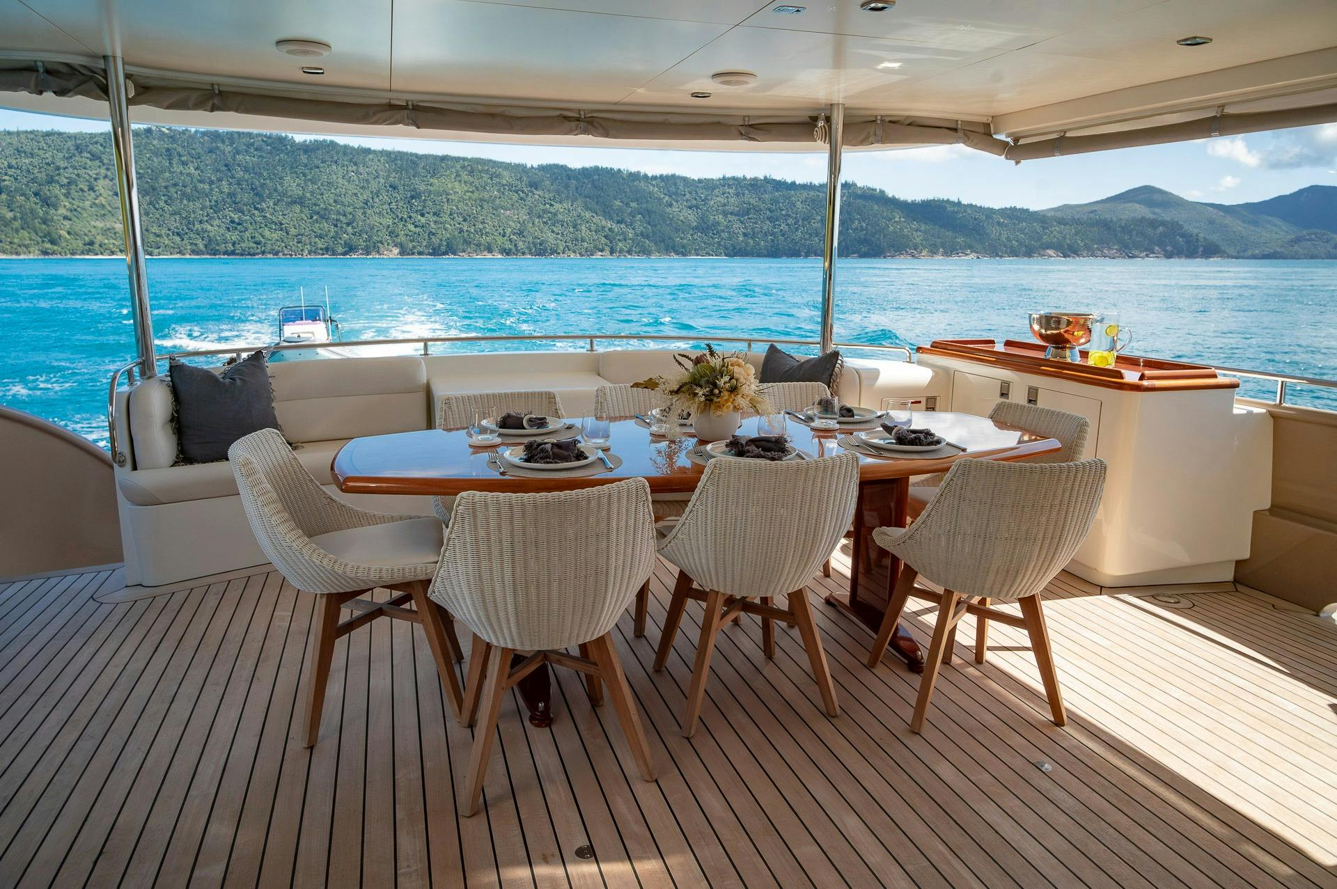 Dining table with eight chairs on back deck of Texas T motor yacht with Whitsunday Islands view