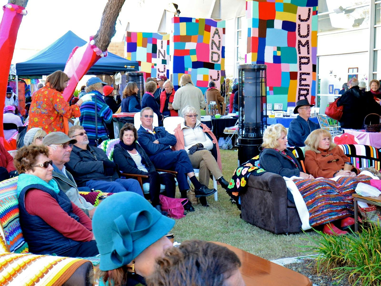 A market scene with people sitting on sofas outside A market scene with people sitting on sofas outside