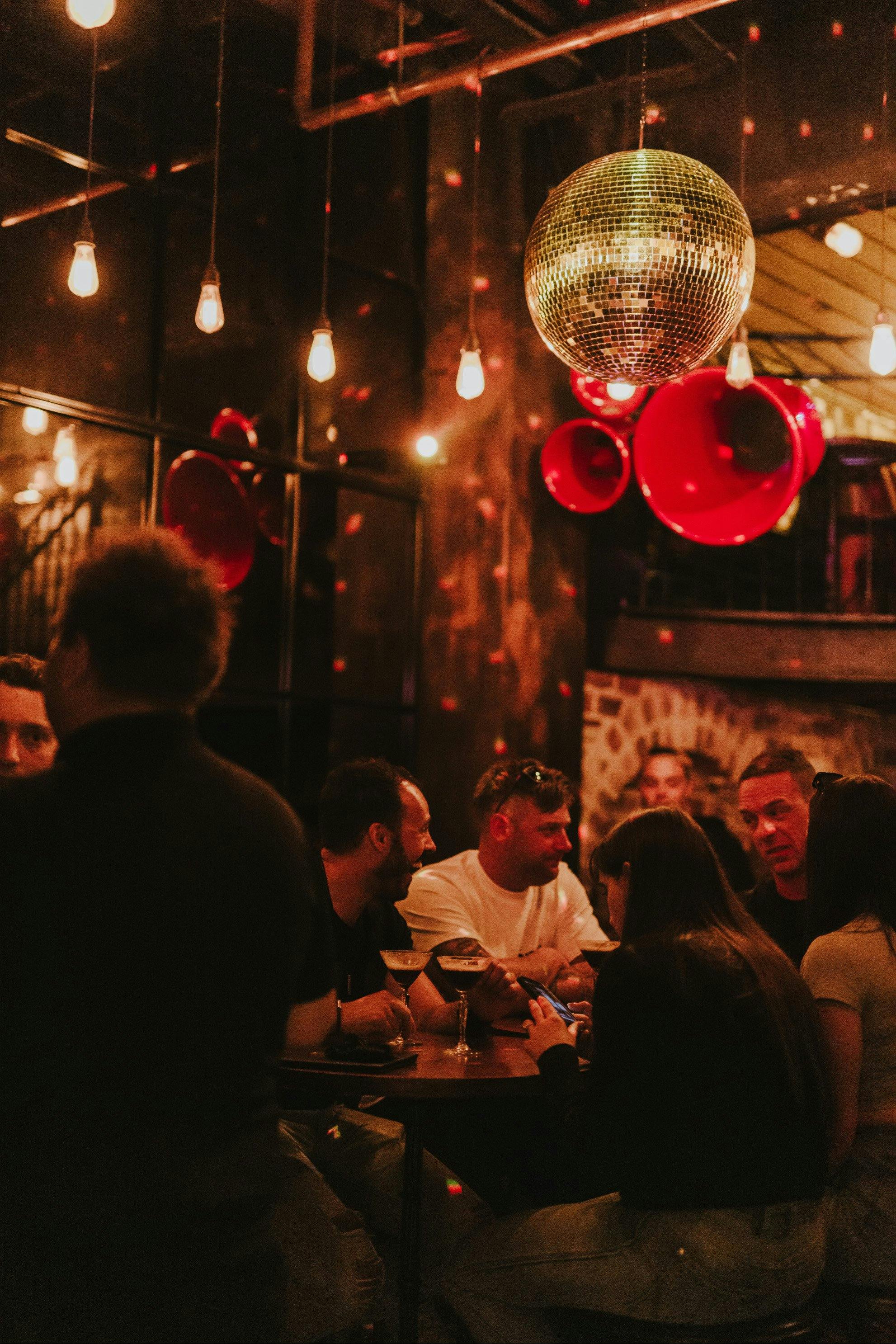 A silver disco ball is suspended above bright red speakers