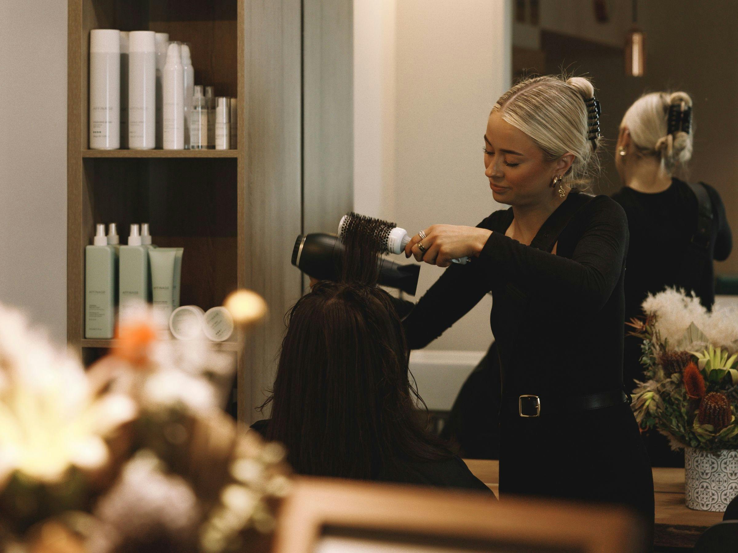 고객에게 블로우 웨이브를 시술하는 아스트라 사내 미용사의 이미지