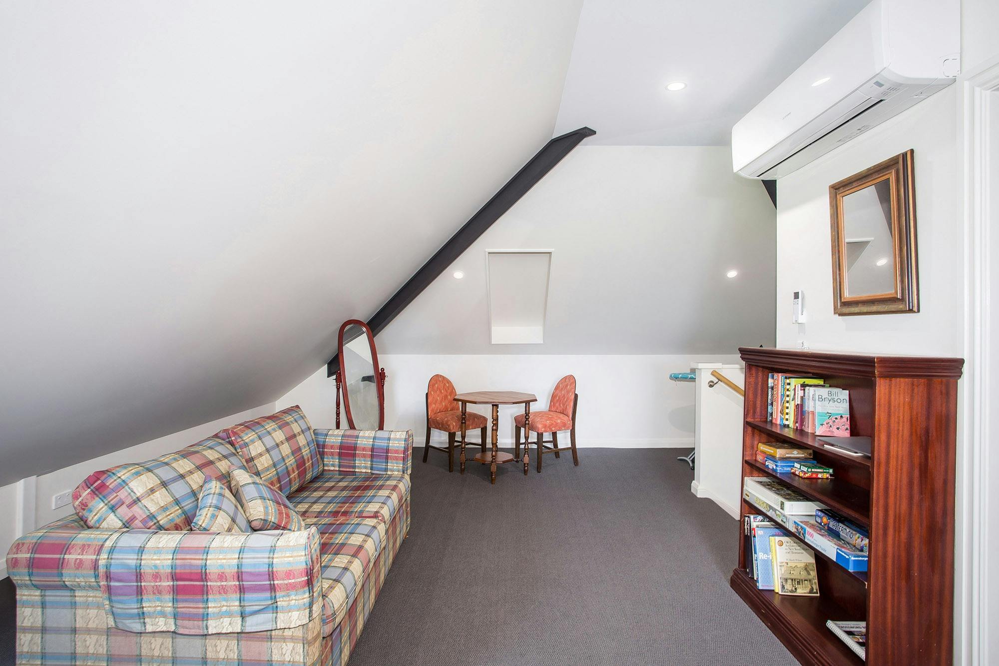 Sofa, book shelf with books, desk and two chairs, ironing board