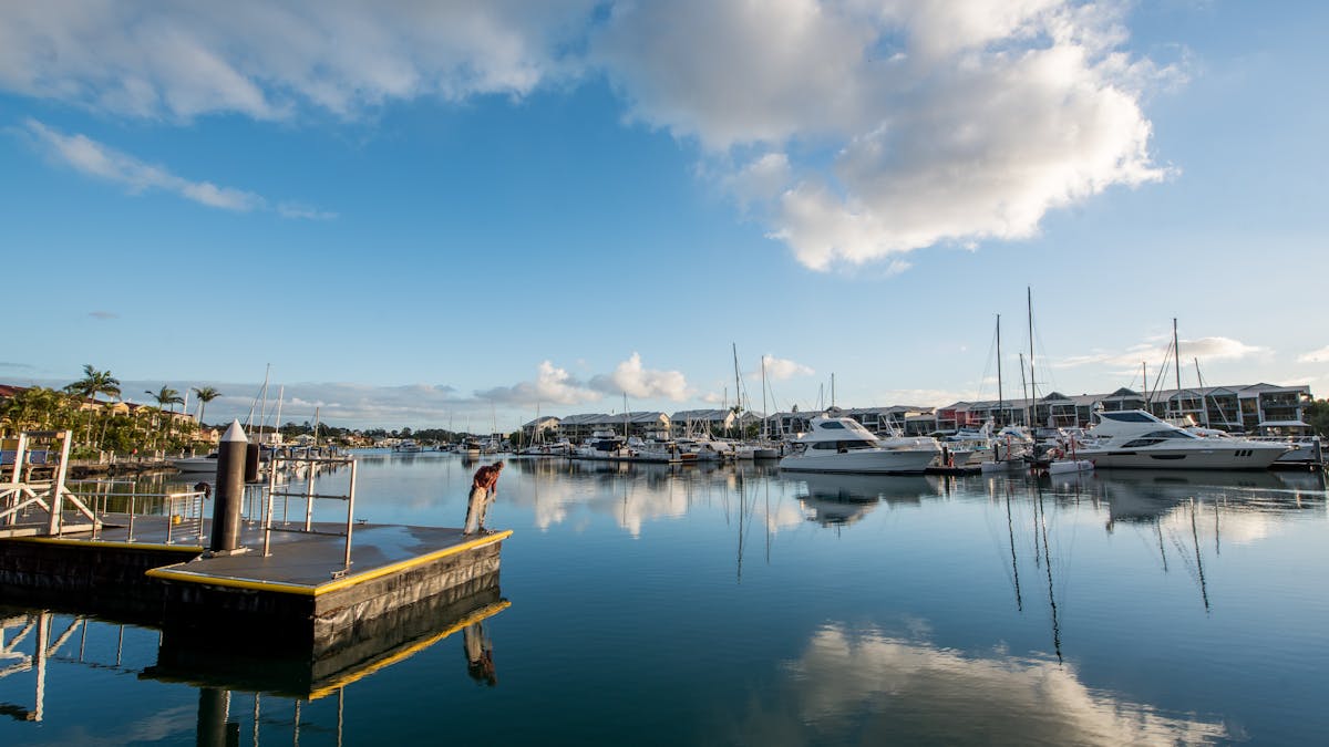 Man at Raby Bay Harbour near Cleveland Station, calm waters with moored boats and homes Man at Raby Bay Harbour near Cleveland Station, calm waters with moored boats and homes