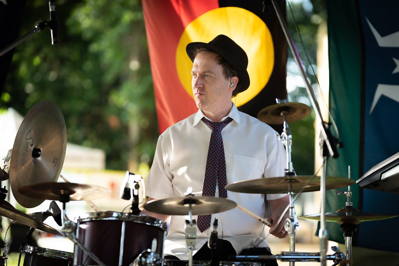 Drummer playing with Aboriginal flag in the background