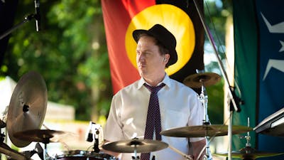 Drummer playing with Aboriginal flag in the background