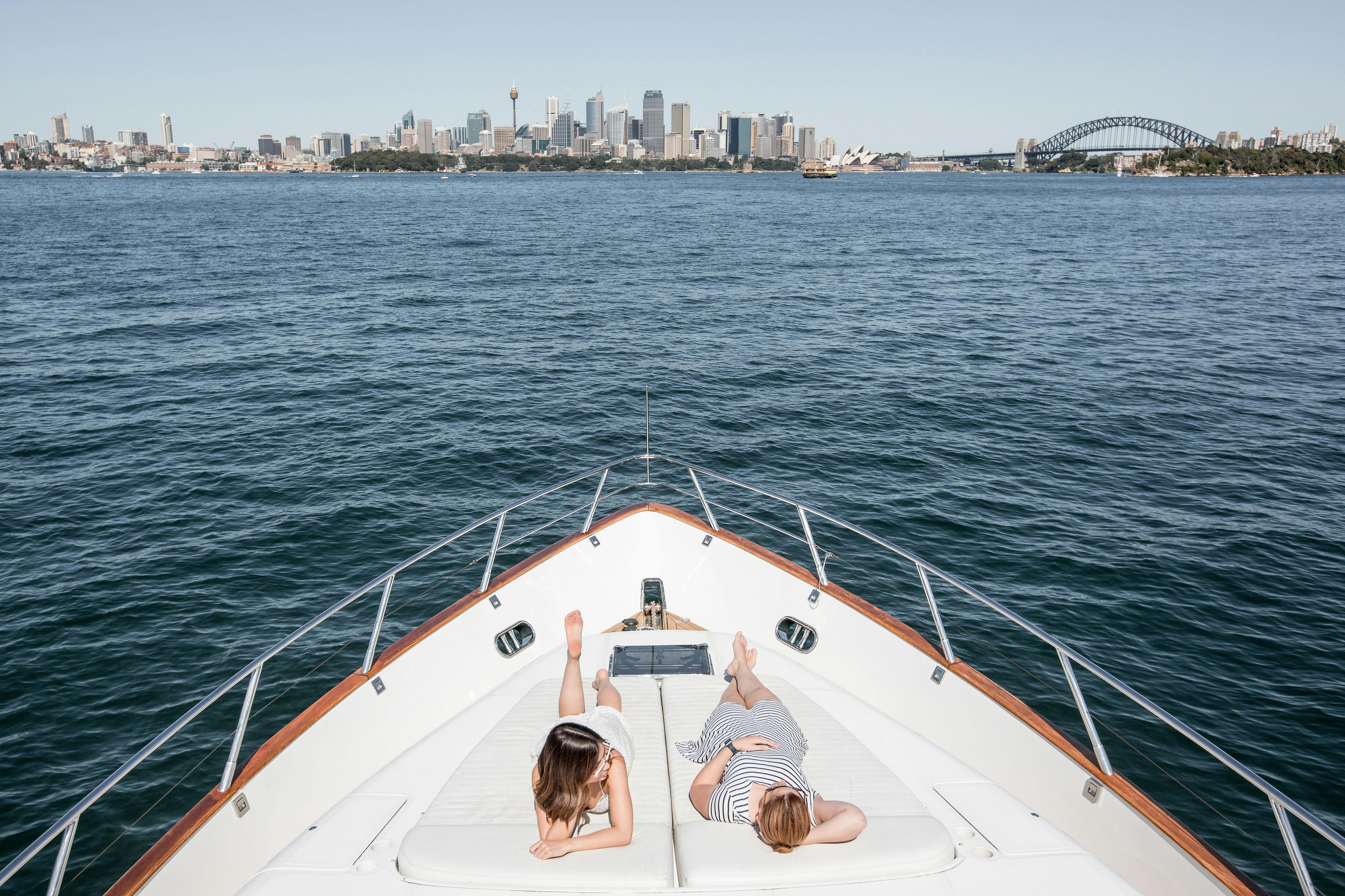 guests relax on Enigma's bow sunbed on sydney harbour