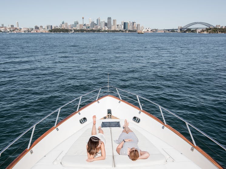 guests relax on Enigma's bow sunbed on sydney harbour