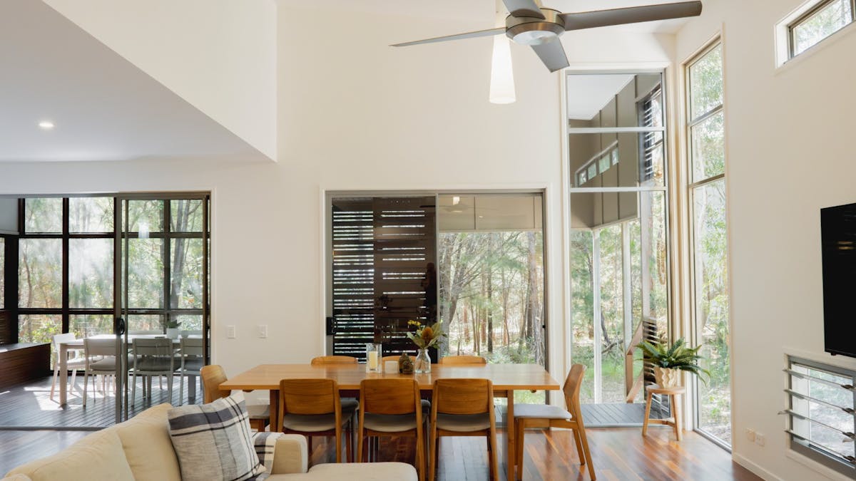 Spacious house interior with lounge, dining area, and large windows overlooking serene bushland view
