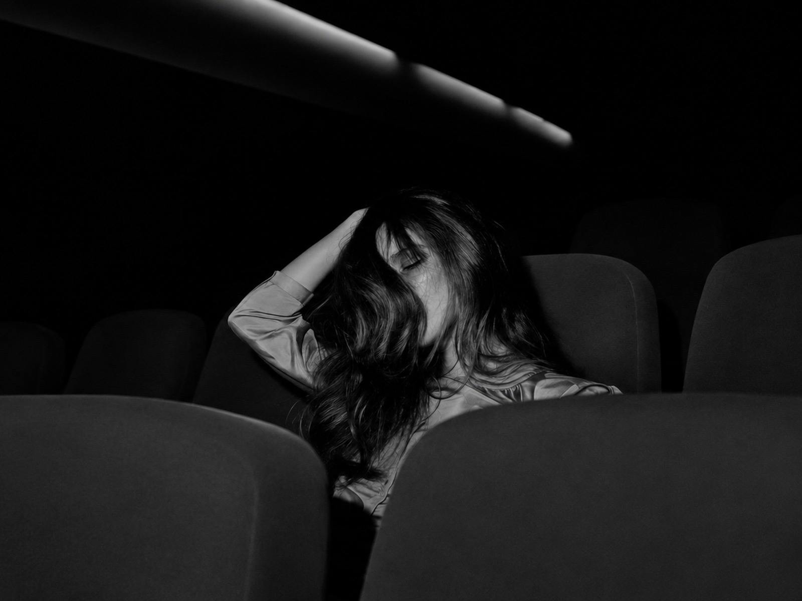 black and white photo of woman in theater with her hand in her dark har draped over her face
