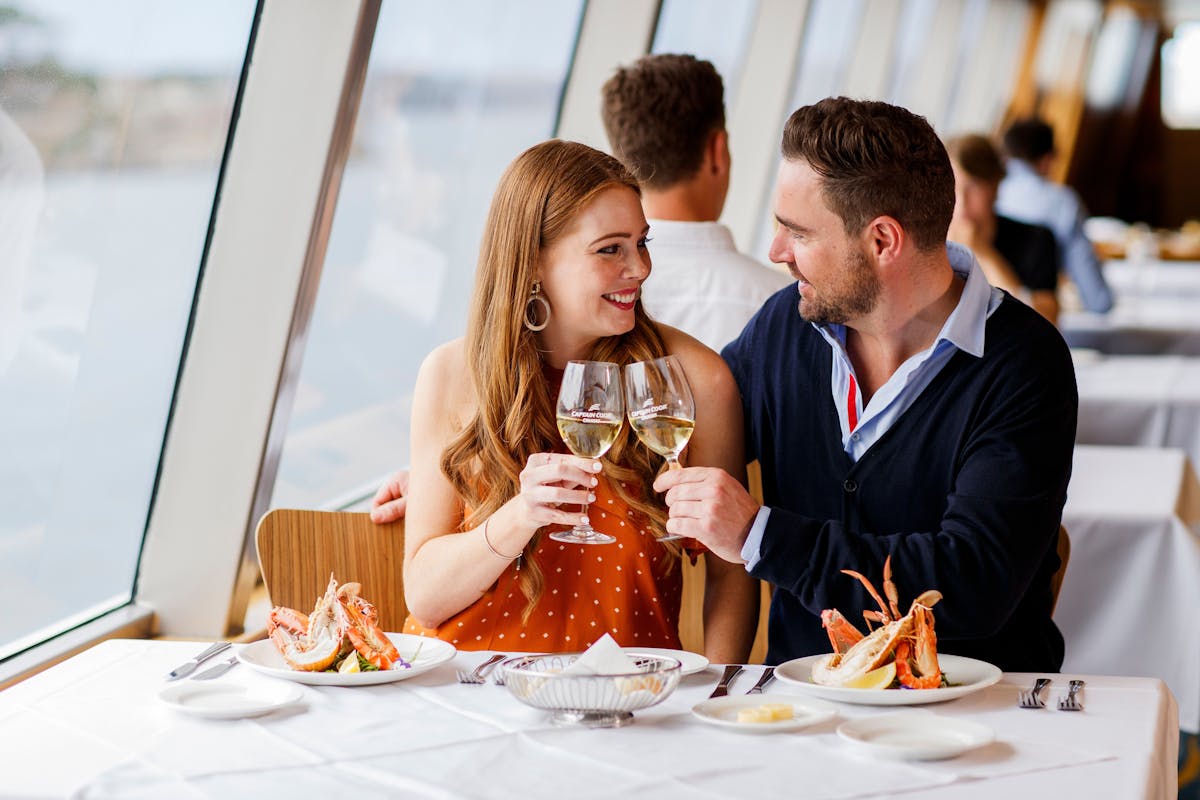 Couple enjoying wine and food onboard Captain Cook Cruises
