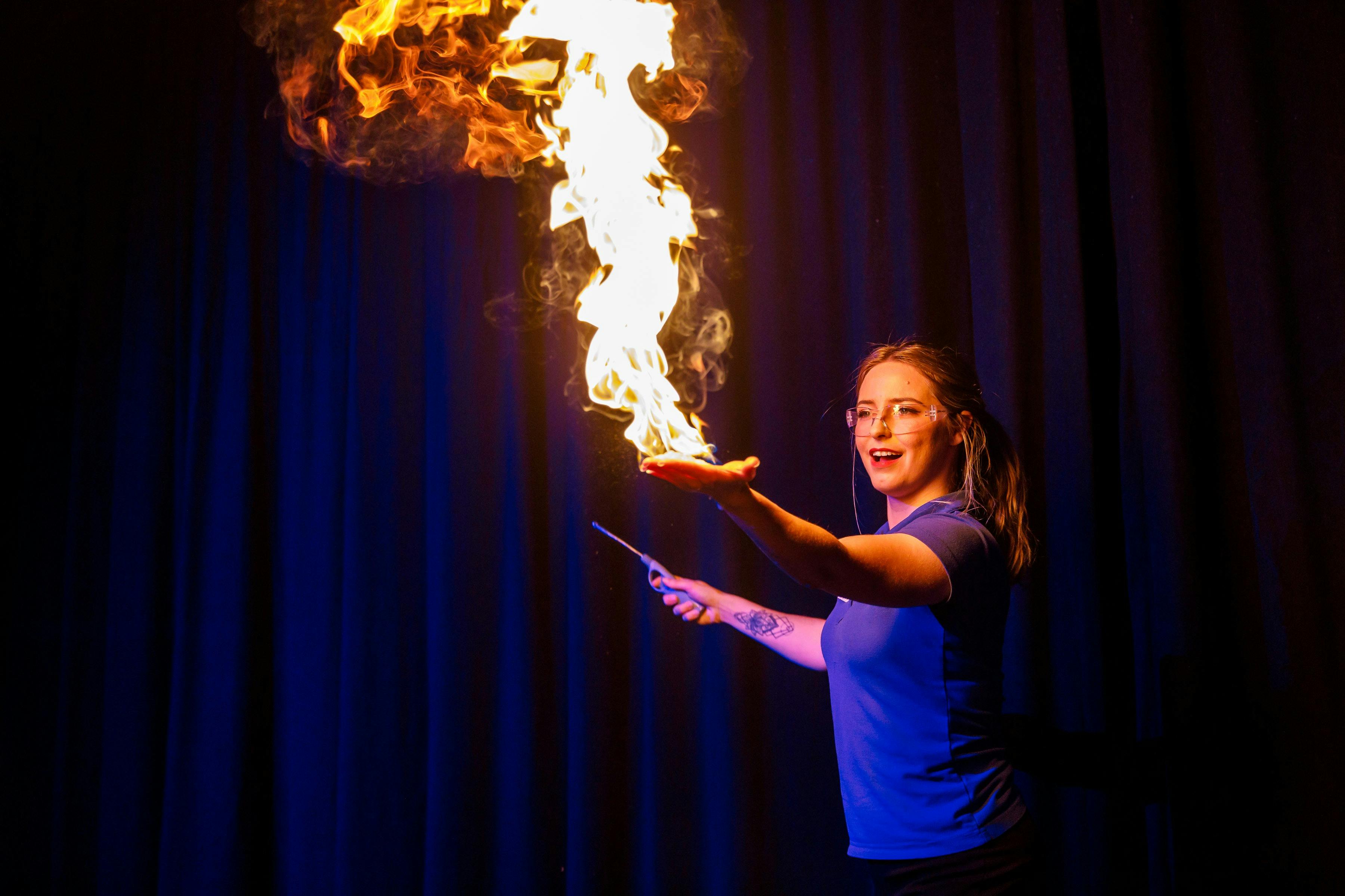 Science presenter demonstrating hand on fire.