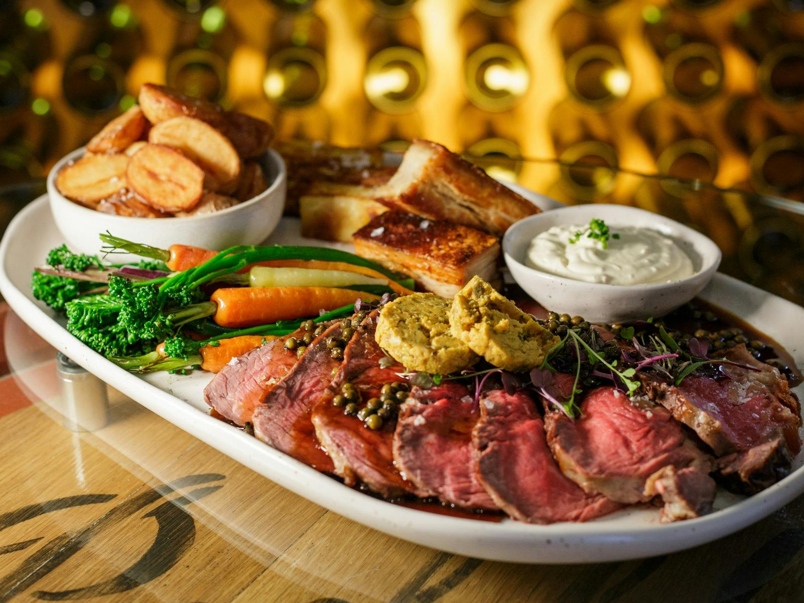 Platter of sliced roast meat with vegetables and sides.