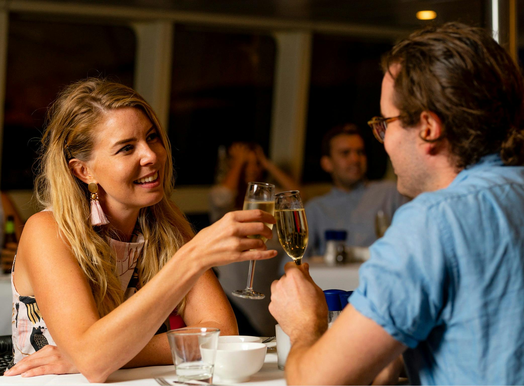 Couple seated at a table toasting each other with a glass of bubbles