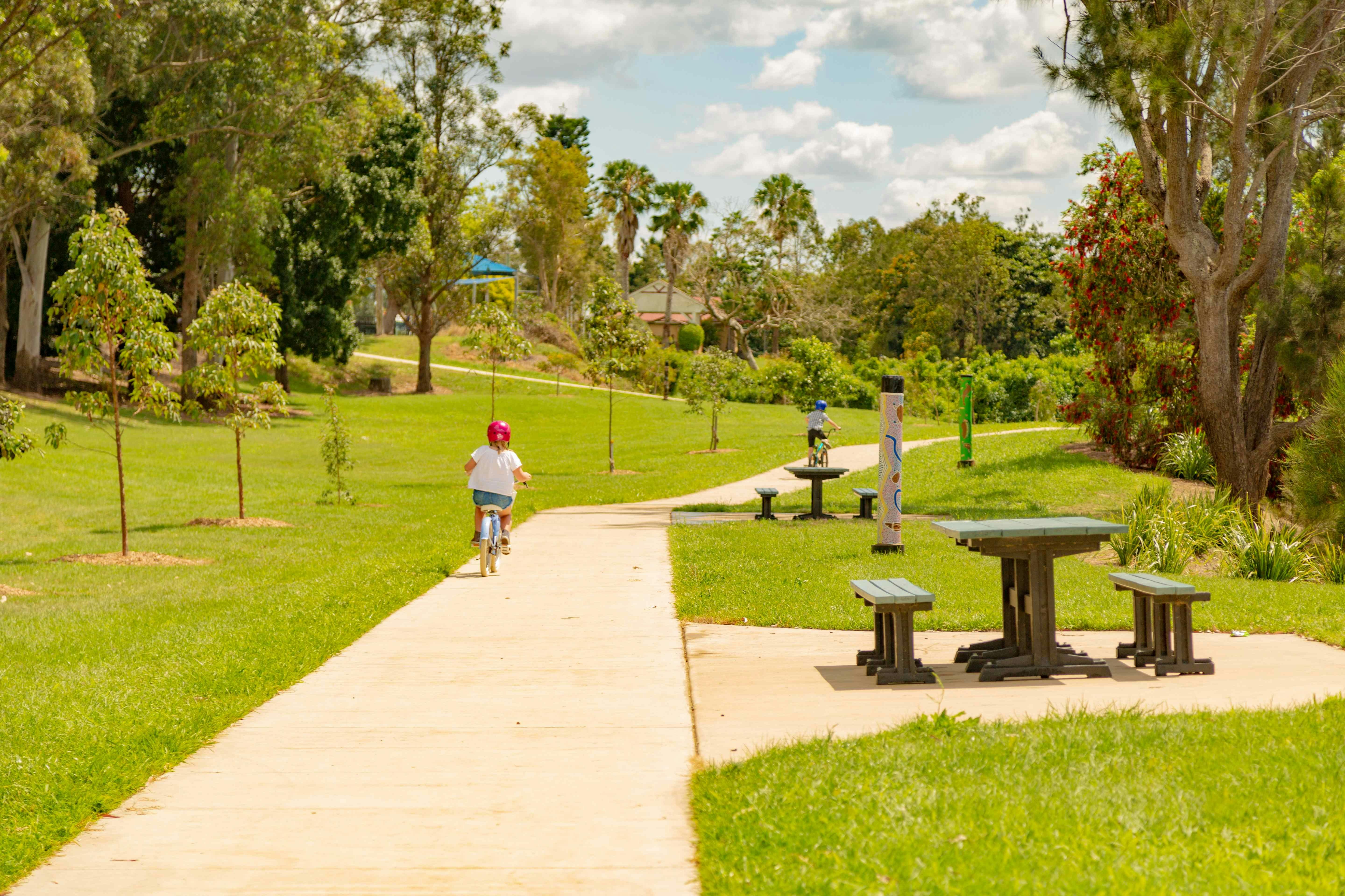Child riding a bike through the park.