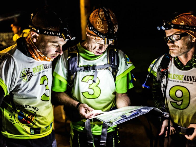 Three team mates looking at their map in the dark