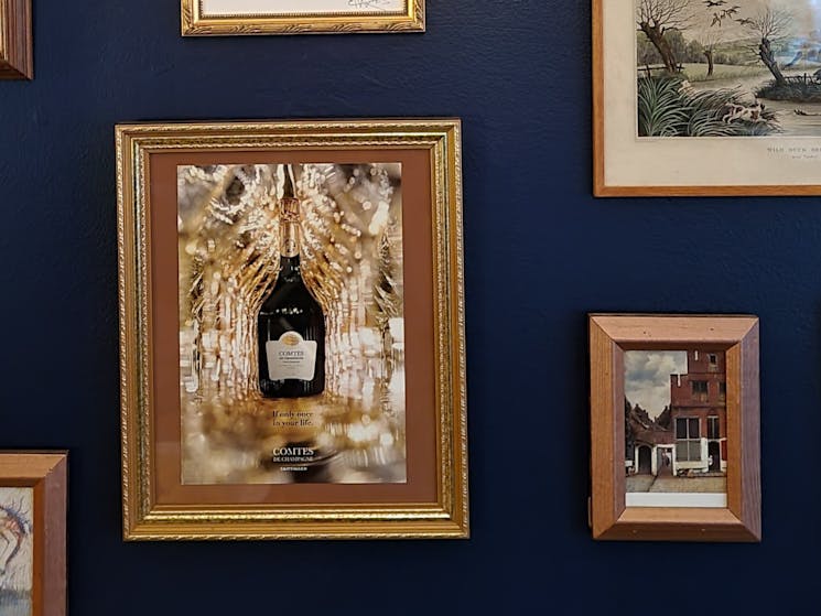 Royal blue wall, with gold frame pictures of wine bottles