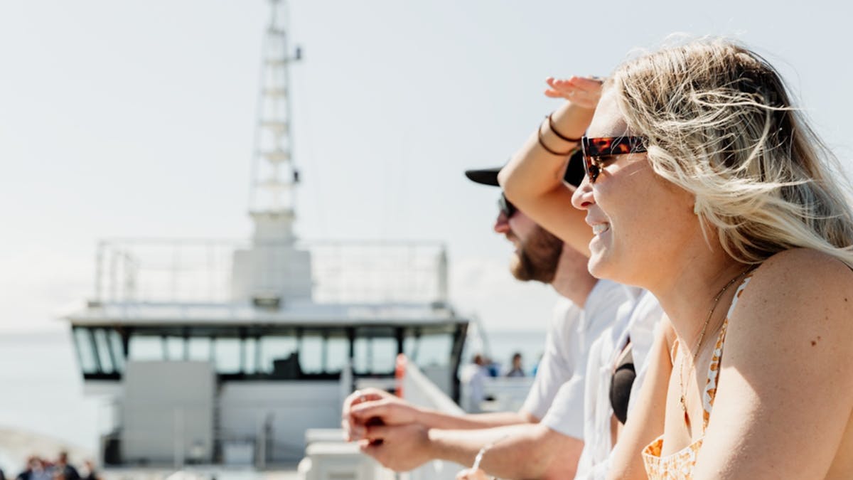 Passengers enjoying the view from the viewing deck of a ferry