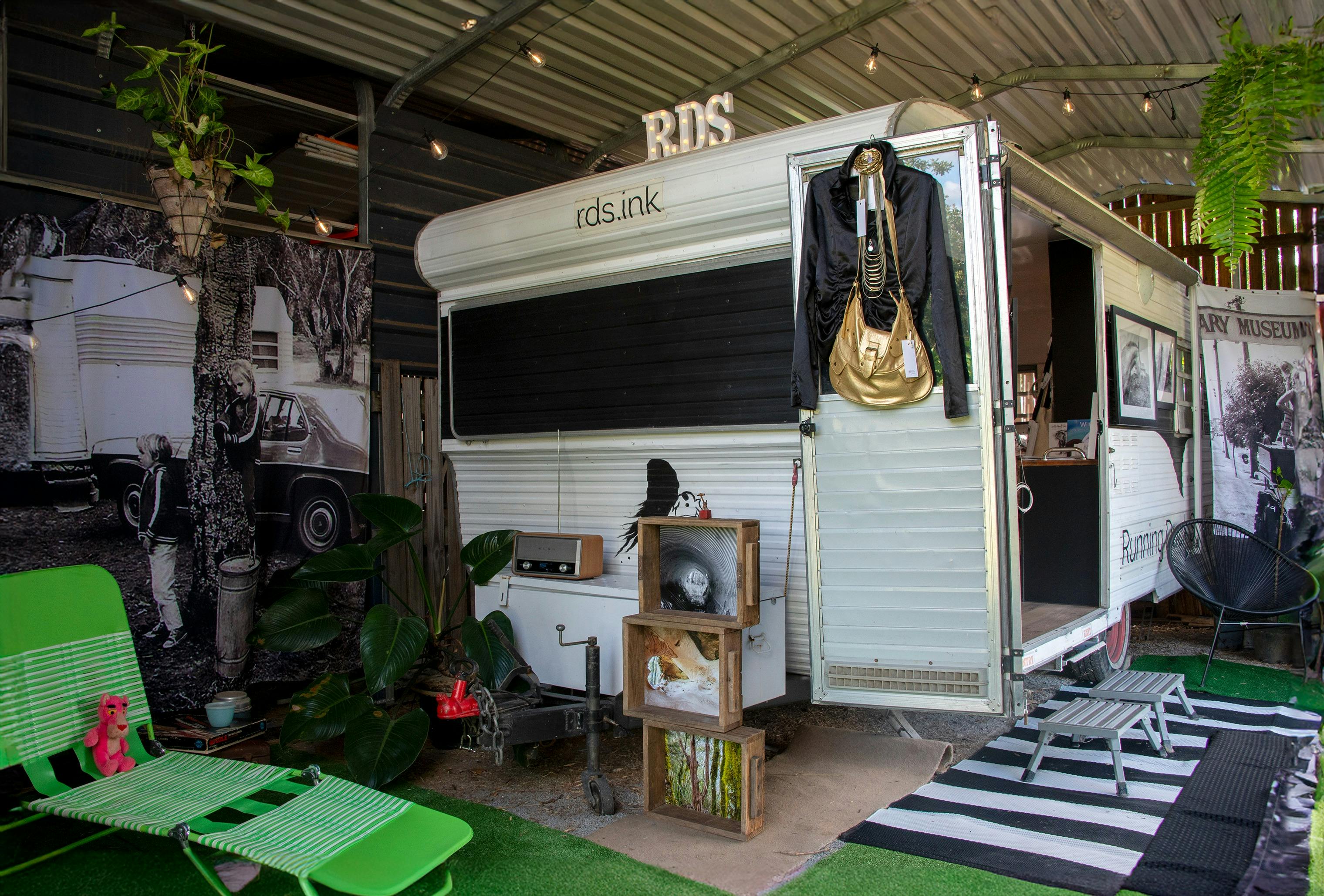 Black and white 1970's caravan set up as quirky gallery space in a shed
