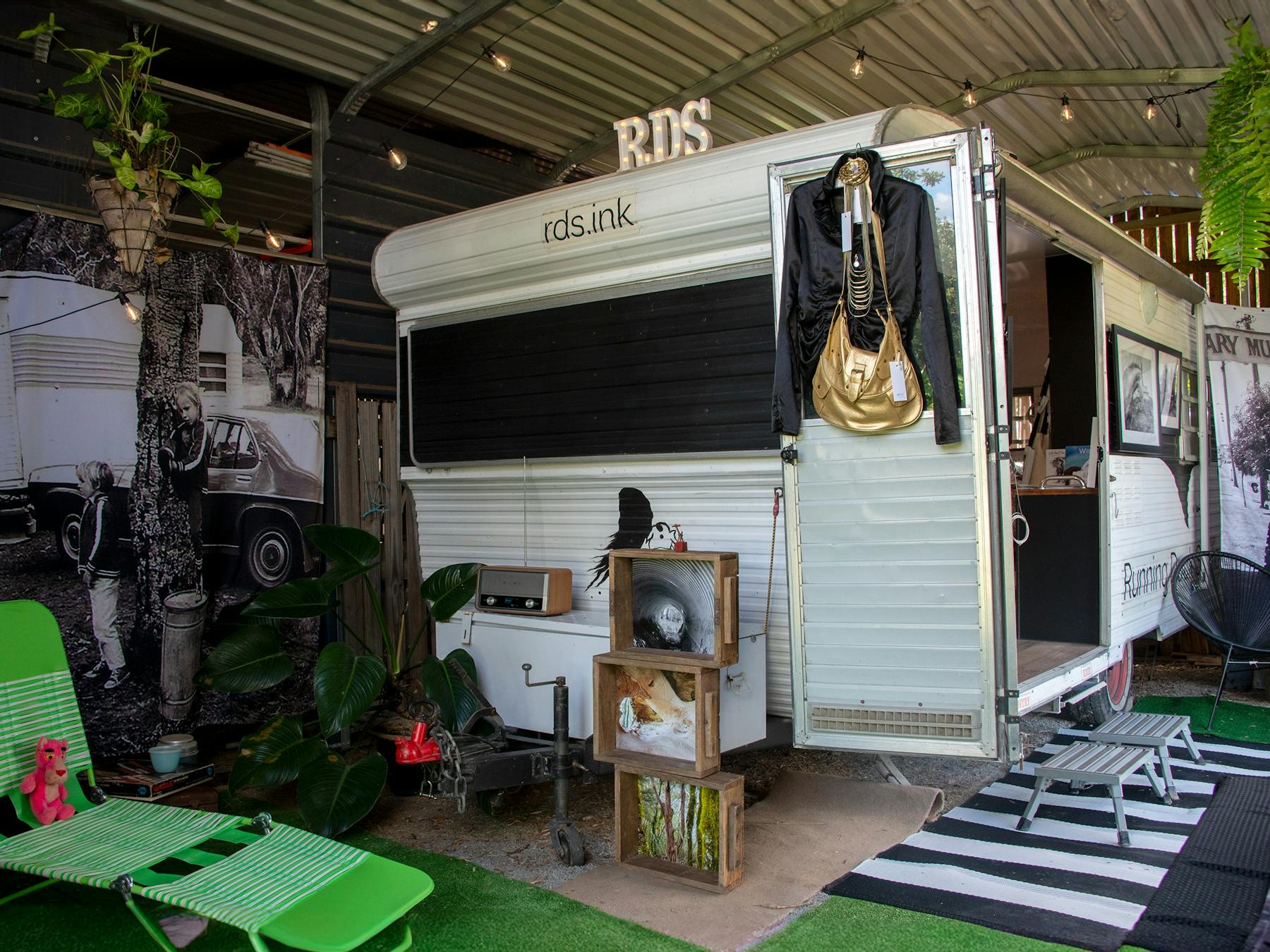 Black and white 1970's caravan set up as quirky gallery space in a shed