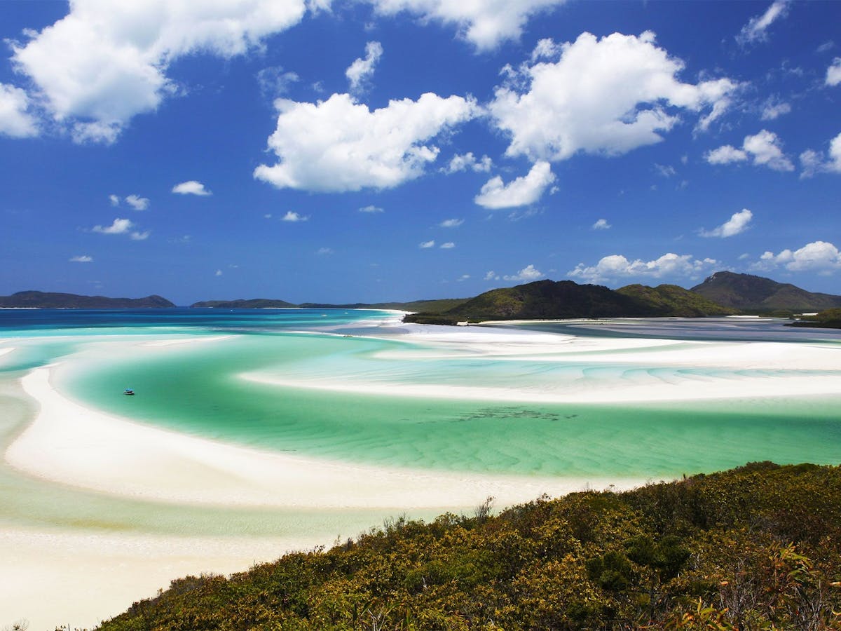 Turquoise water and white sand with islands in the background.
