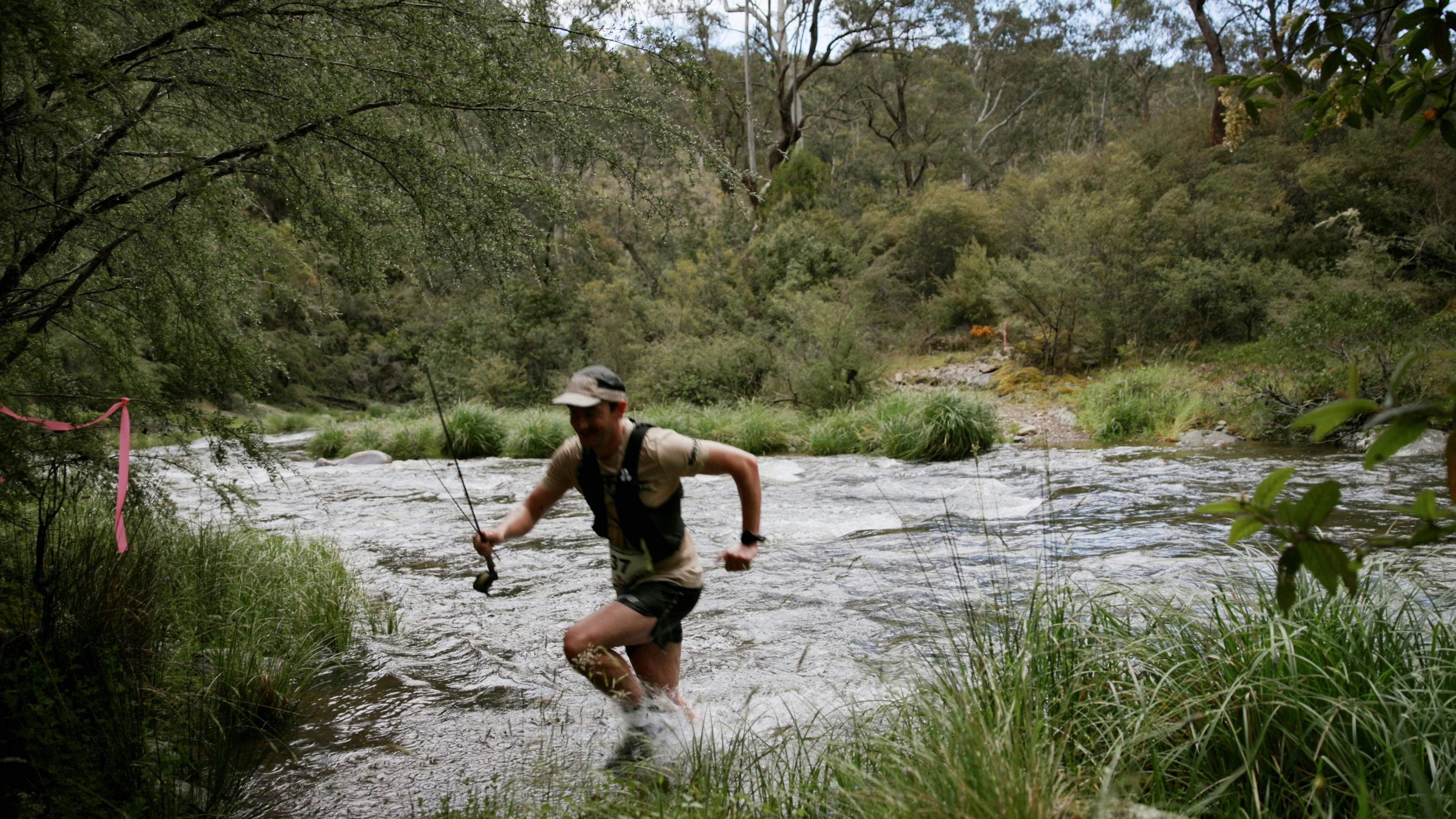 Runner with fishing rod crosses river