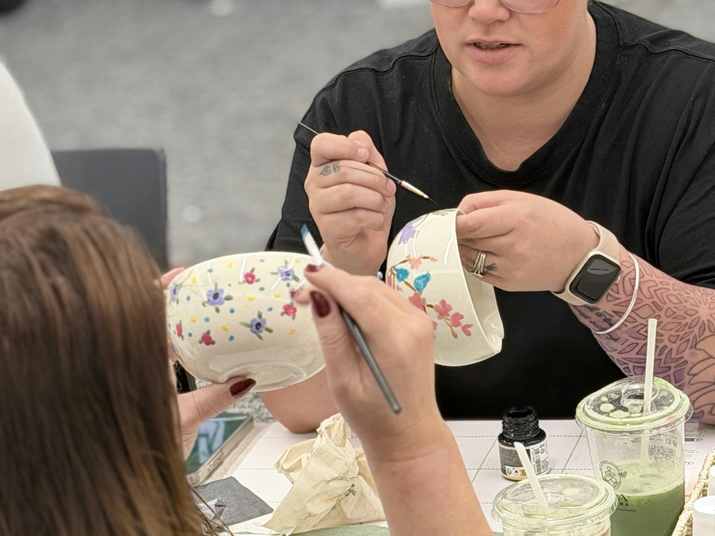 Guest hand-painting a ceramic cup at a NOA Matcha workshop