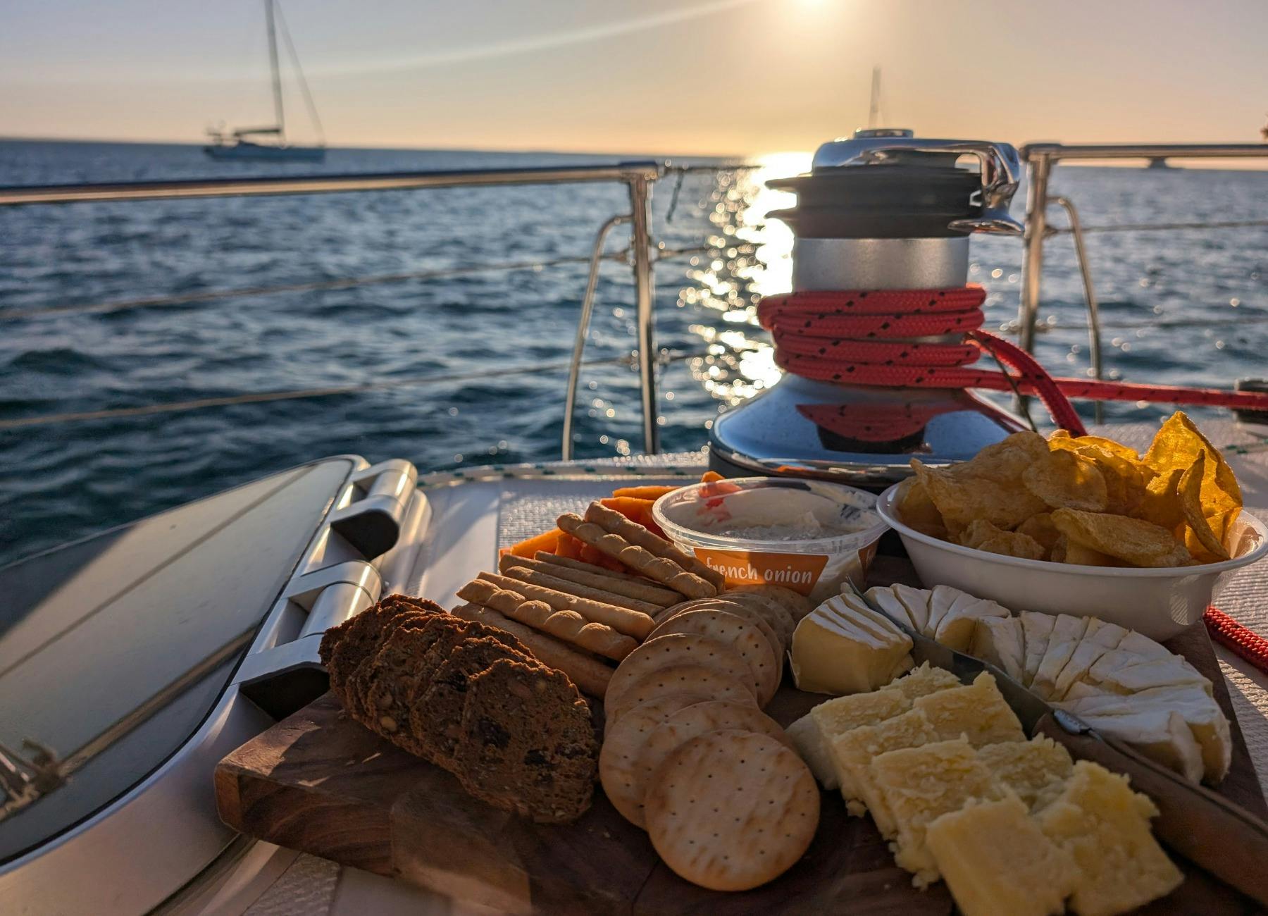 Photo of mixed savoury nibbles platter with ocean sunset in background.