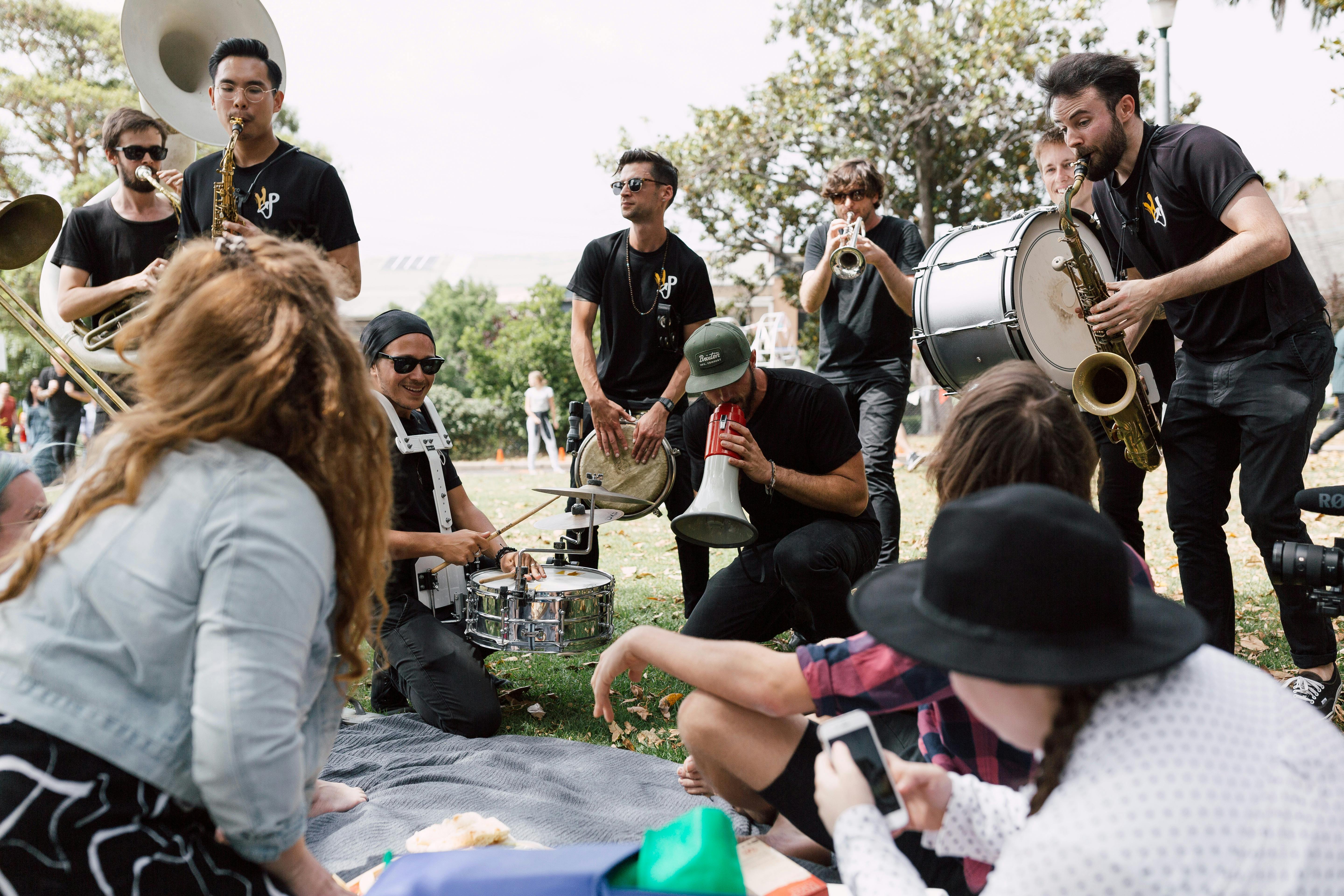 A group of musicians plays to a woman on a picnic blanket