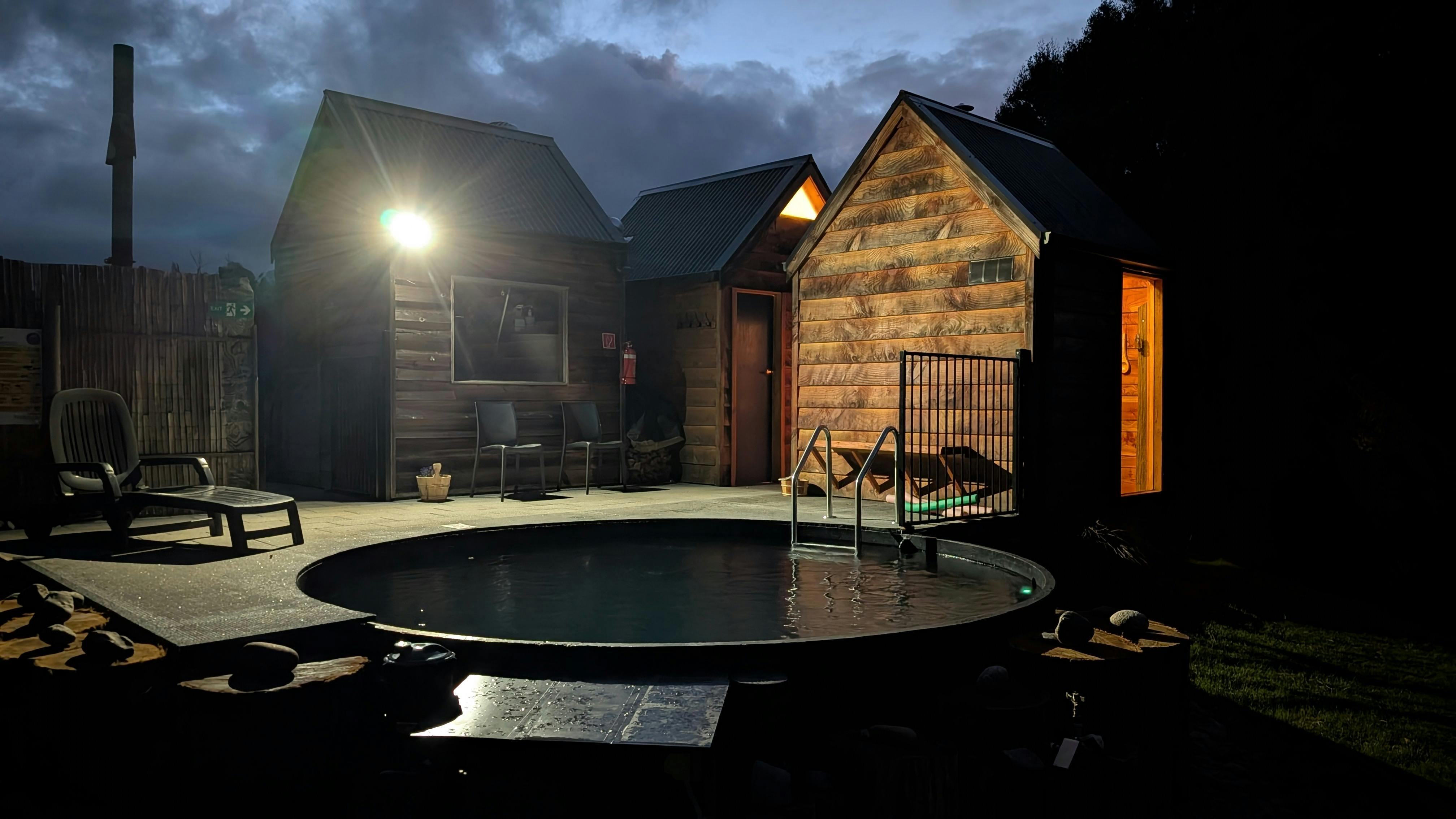 Night photo outside sauna with a view of the sauna, pool, bathroom and hydro generator shed.