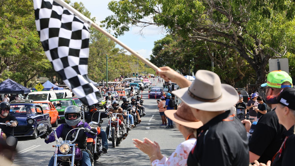 Motorcycles and cars in a street parade watched by crowds during Rockynats.
