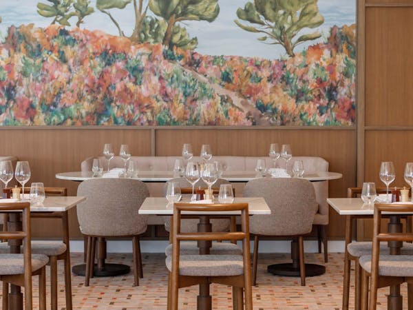 Empty restaurant with tables set for dinner. Australian native mural on wall.