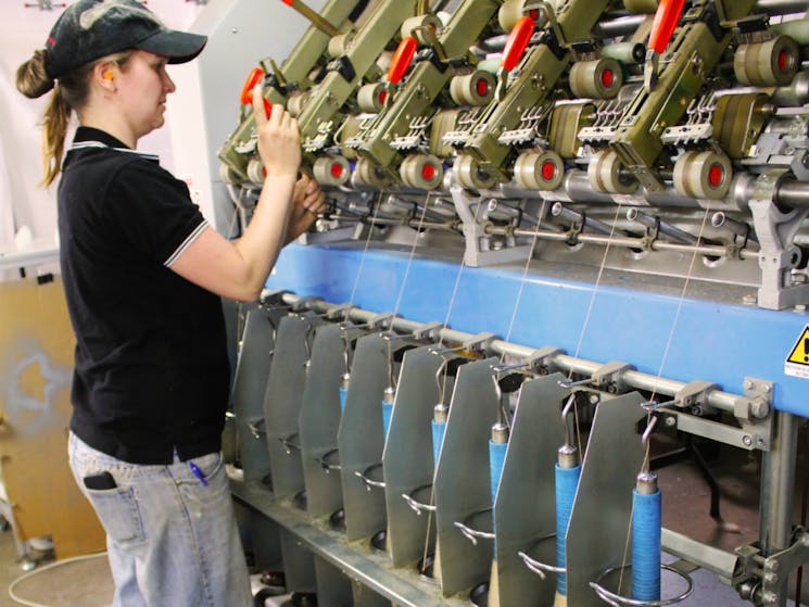 Nadine using the spinning frame to spin yarn