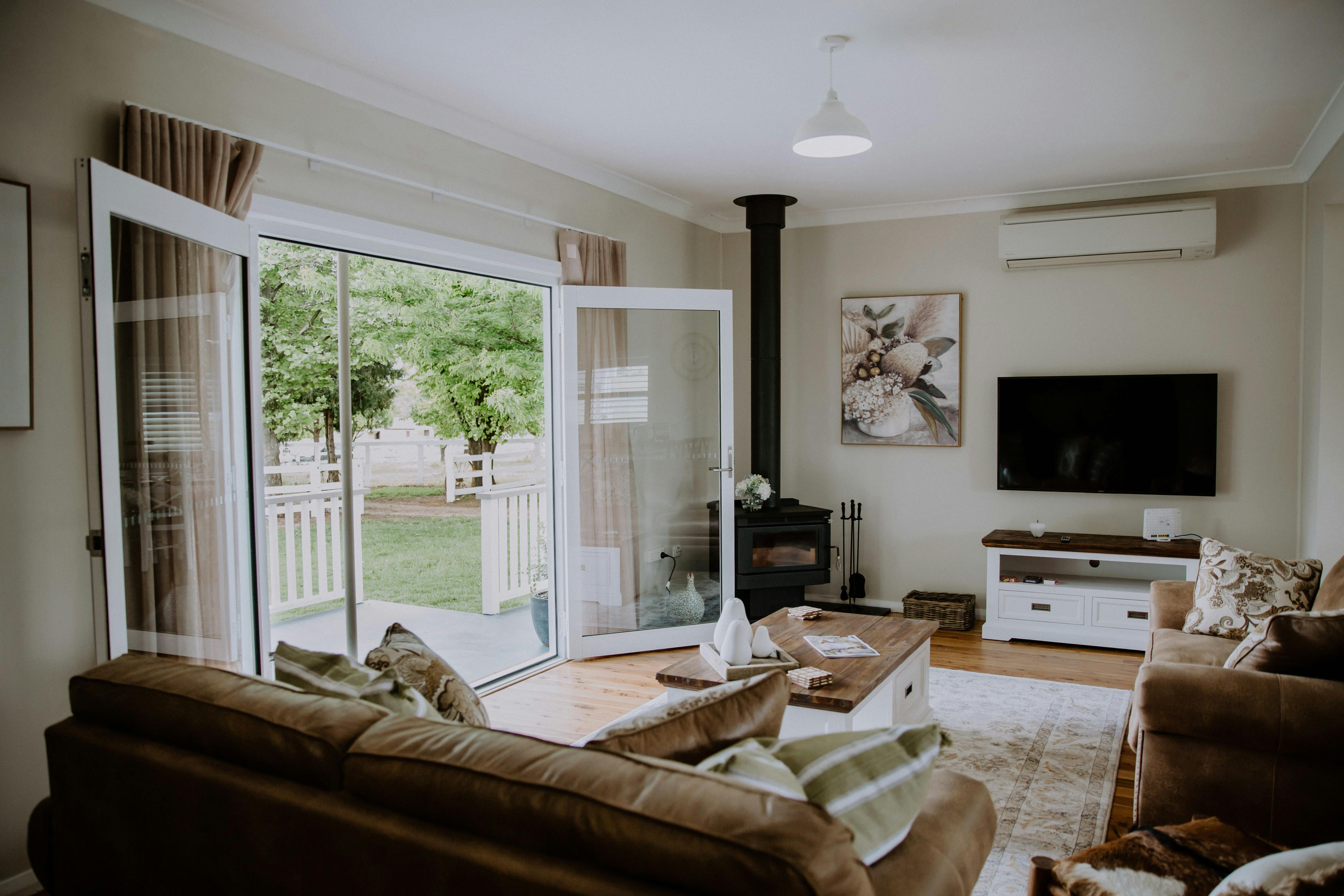 A relaxing lounge room with a wood stove and TV, French doors thrown open to a garden at Gooree Park