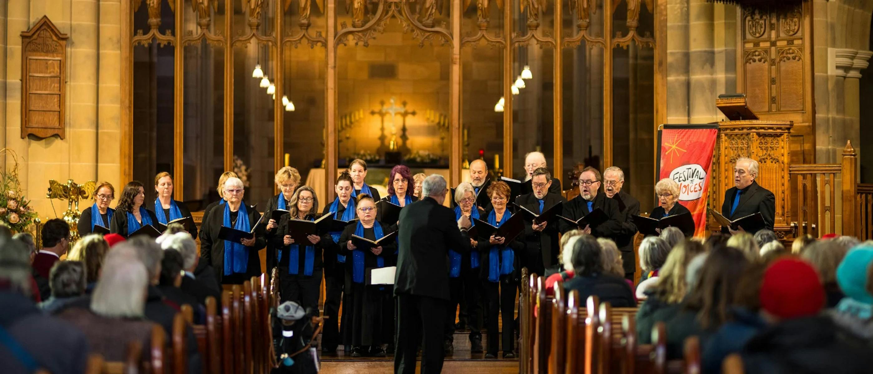 A choir dressed in blue and black singing in a cathedral