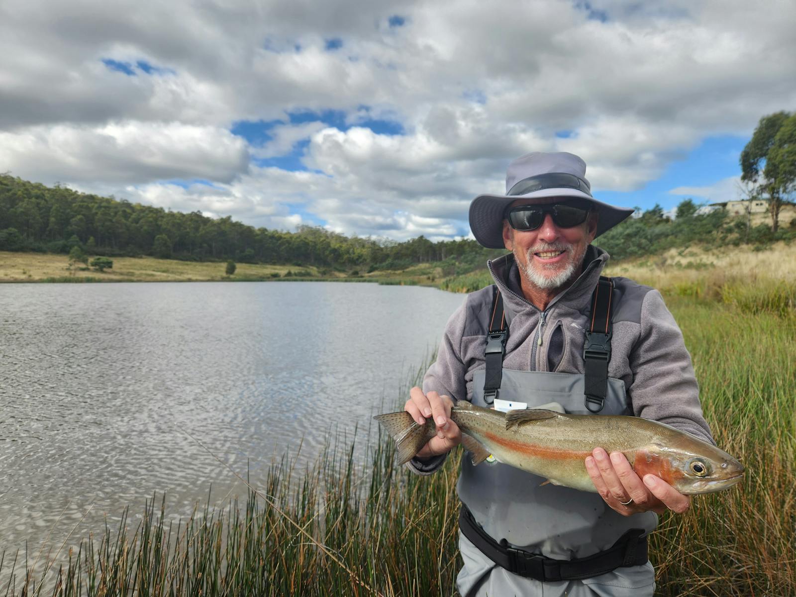 A fisherman holding a rainbow trout he has just caught at Twin Lakes Private Fishery