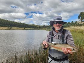 A fisherman holding a rainbow trout he has just caught at Twin Lakes Private Fishery