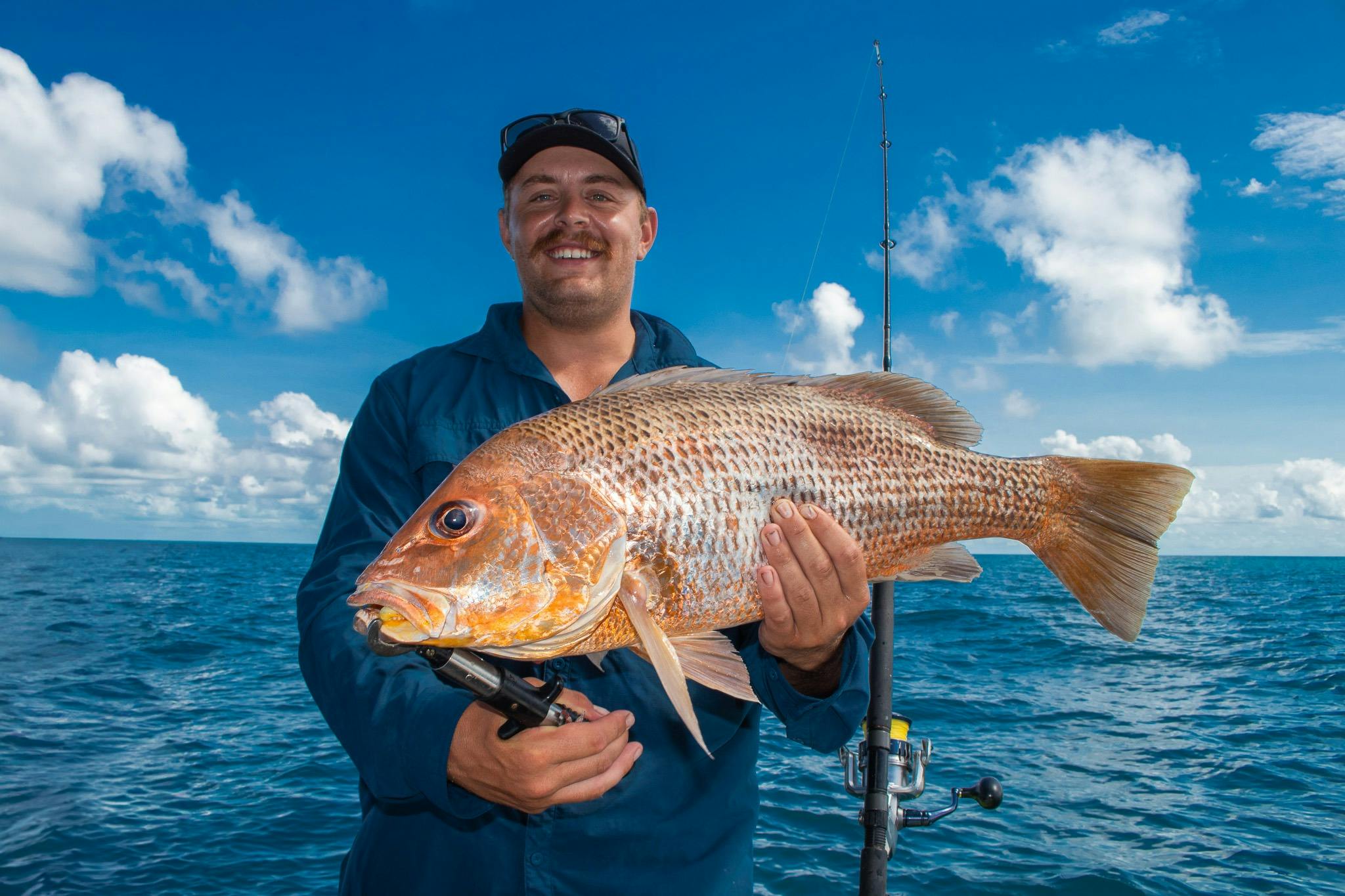 A proud angler holds up a beautiful golden snapper, freshly caught in the Top End.