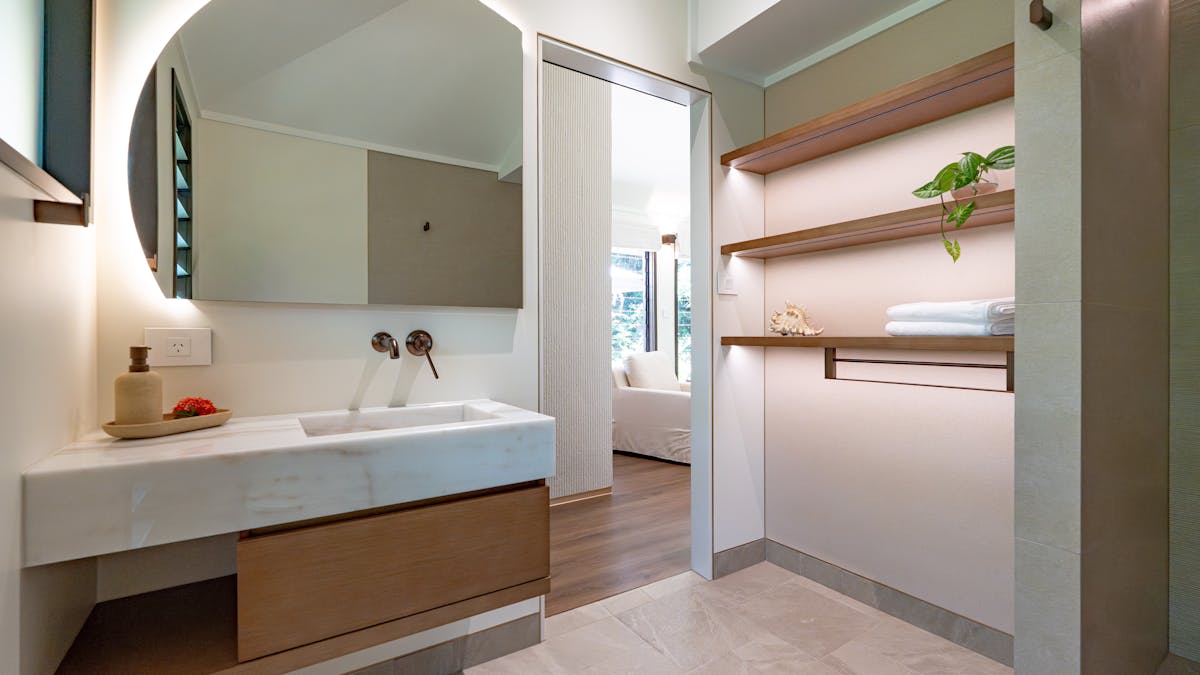 Tranquil ensuite bathroom with timber cabinetry and marble benchtops, spacious shelving & shelving