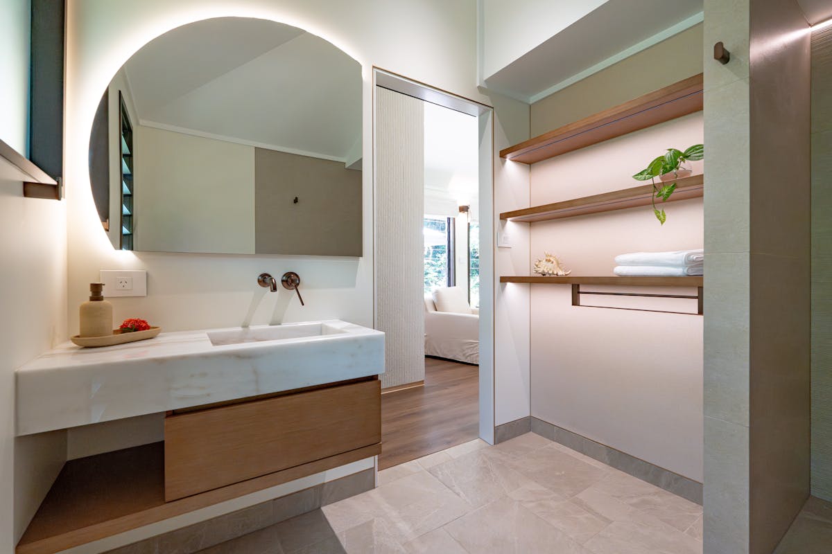 Tranquil ensuite bathroom with timber cabinetry and marble benchtops, spacious shelving & shelving