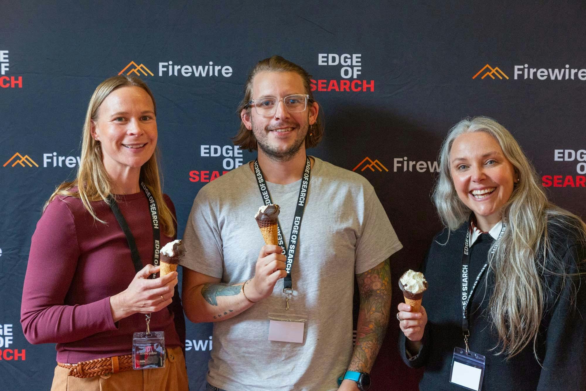 A man stands in between two women, posing for a photo holding vanilla choc top ice creams.
