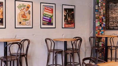 Bar tables against wall with posters in frames hanging on the wall