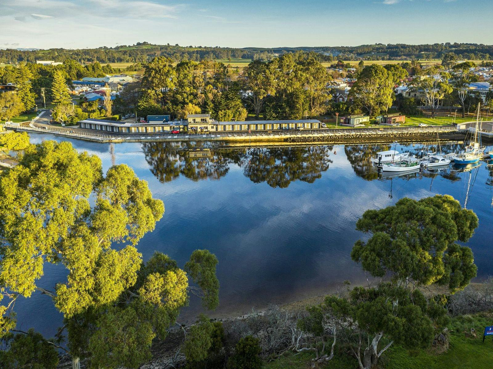 Aerial view of motel on the Inglis river  with blue water in front of motel and trees surrounding
