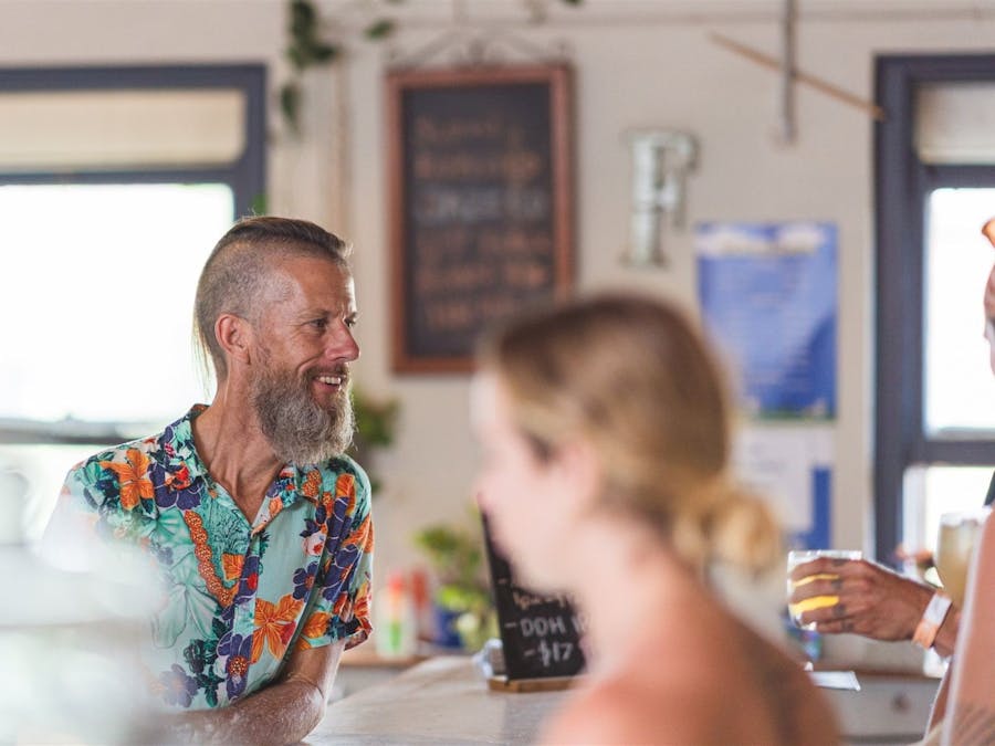 Man sitting at bar smiling with a blurred image of a woman in the foreground