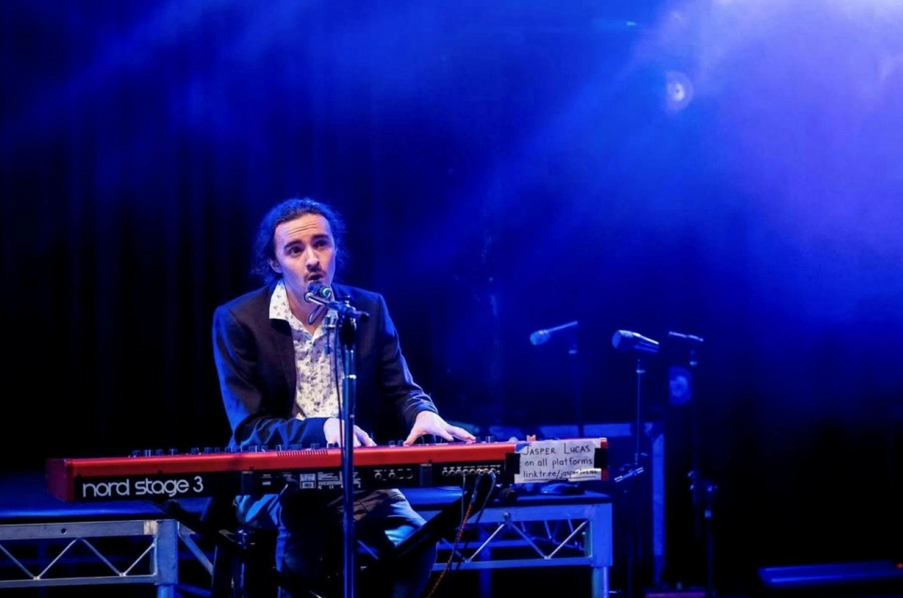 Jasper Lucus on state with a keyboard, singing into the microphone.