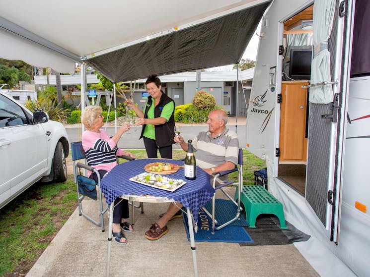Guests enjoying camping in their caravan on a powered site with concrete slab