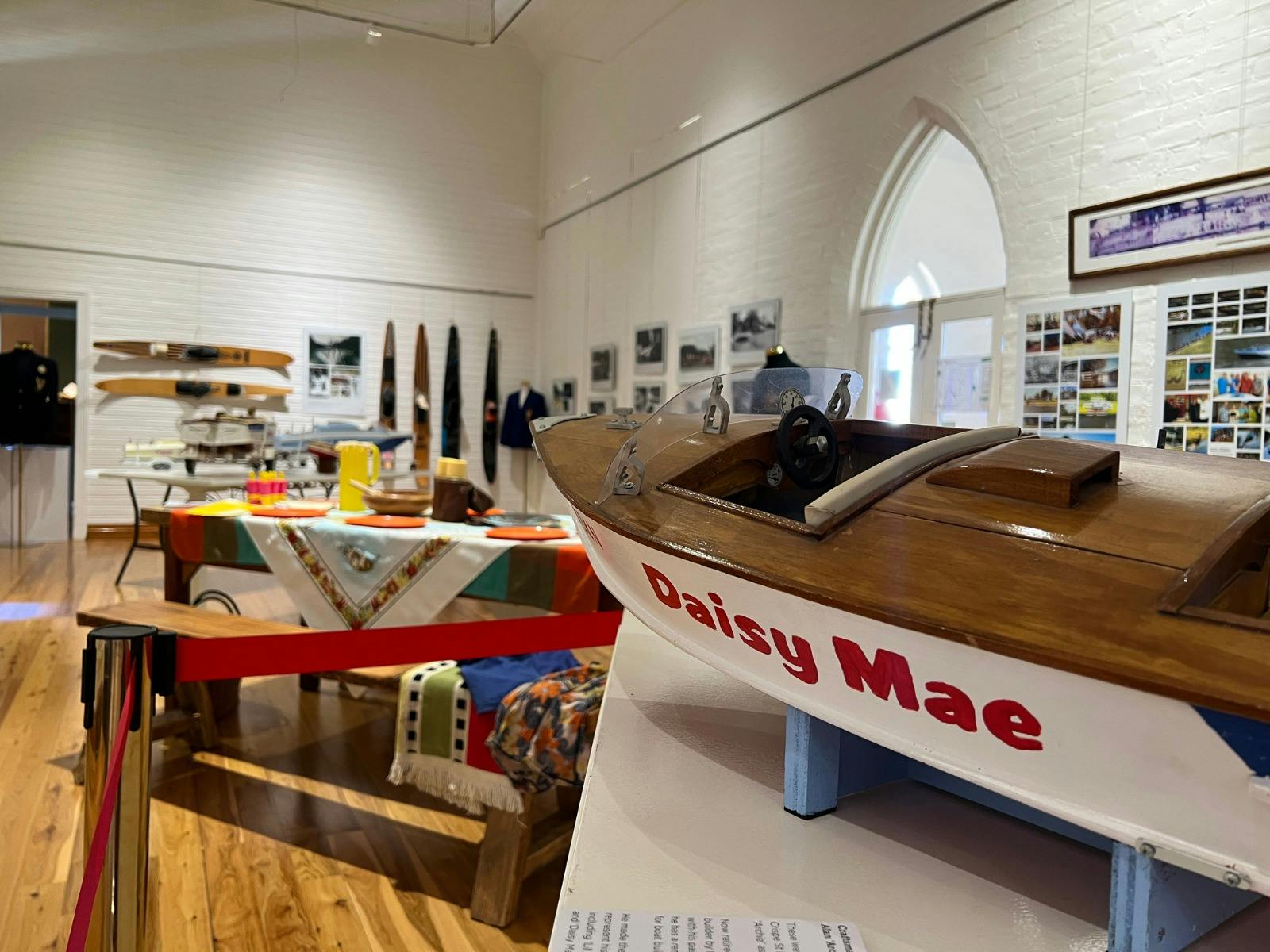 A model board is in the foreground, skis and photos are mounted on the walls