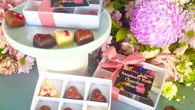 gift boxed artisan chocolate hearts With individual artisan chocolate hearts, flowers in backhround
