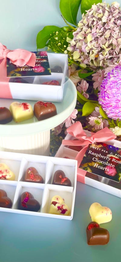 gift boxed artisan chocolate hearts With individual artisan chocolate hearts, flowers in backhround