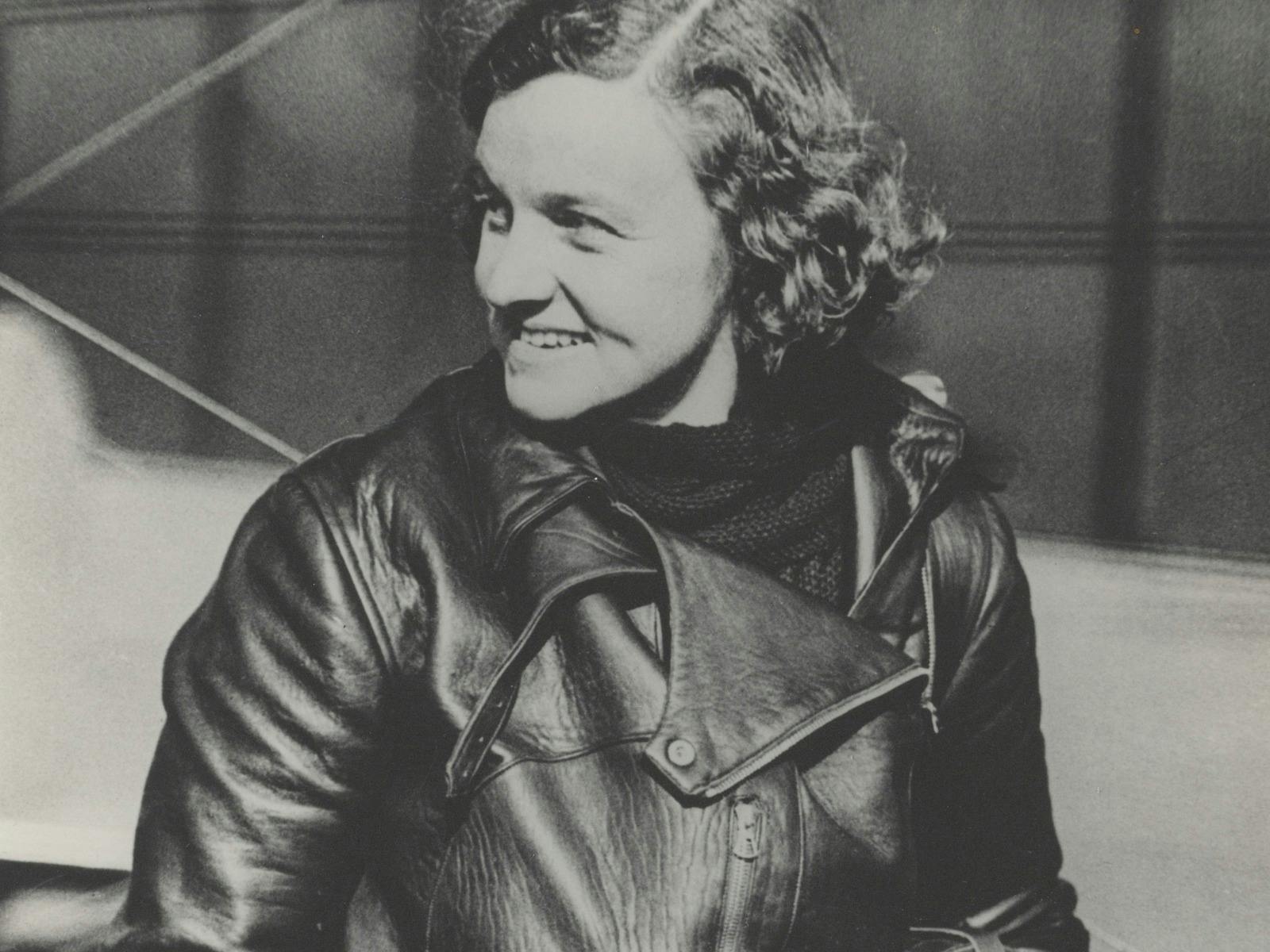 A sepia photograph of a woman with curly hair in flight gear.